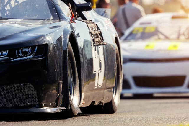Close-up of a black race car on a track with another car blurred in the background